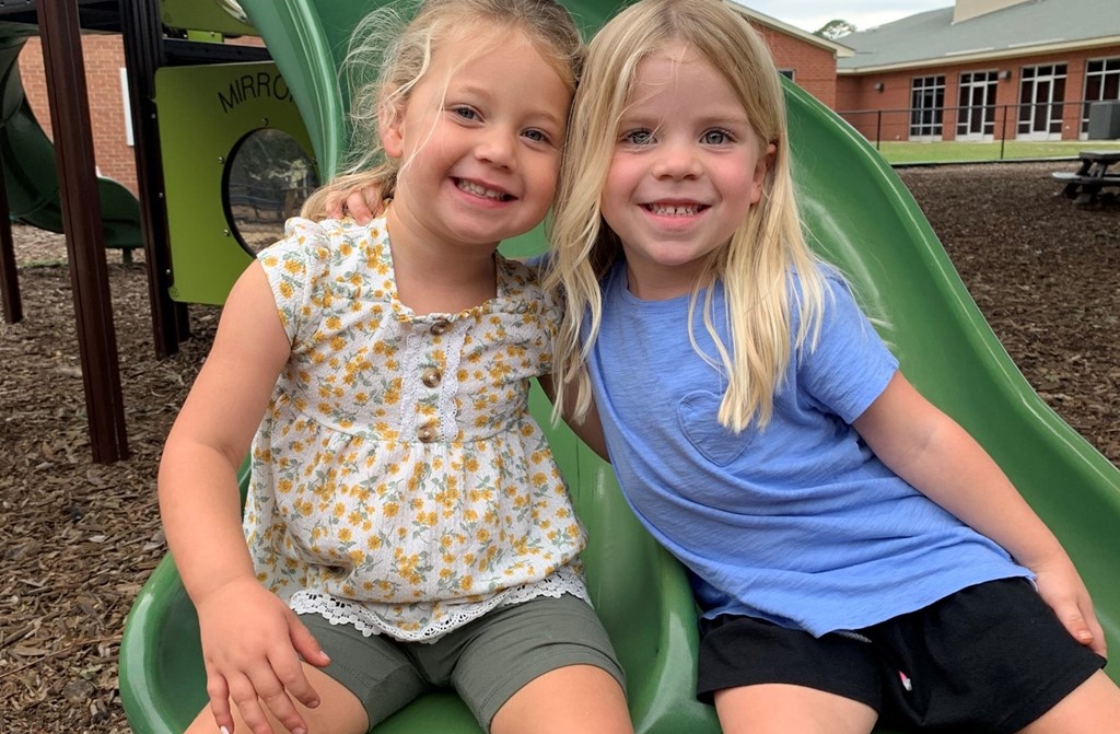 preschool girls pose on slide together